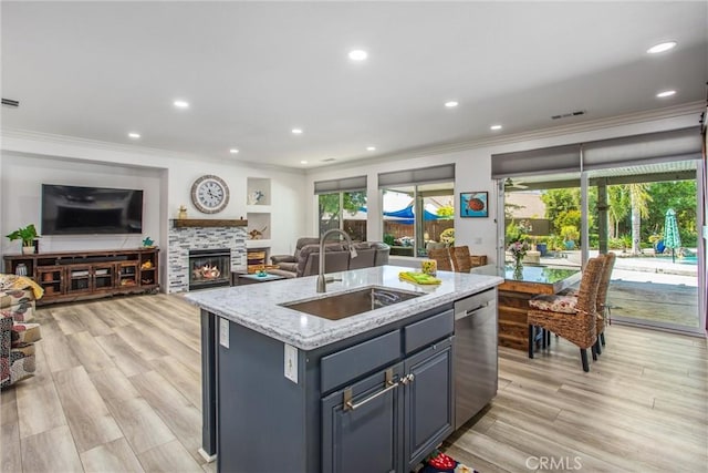kitchen with dishwasher, a sink, crown molding, open floor plan, and light stone counters