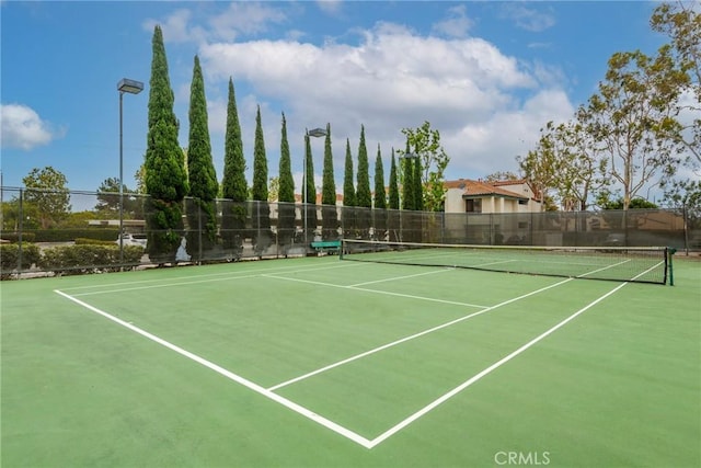 view of tennis court featuring community basketball court and fence