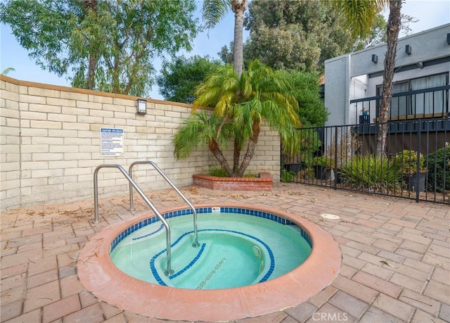 view of swimming pool featuring a community hot tub, fence, and a patio