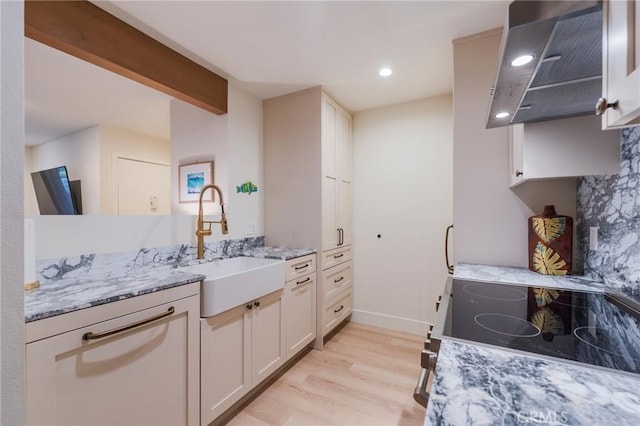215 Wichita Ave Unit 106, Huntington Beach, CA 92648 - kitchen with light wood-style flooring, light stone countertops, stove, wall chimney exhaust hood, and white cabinets