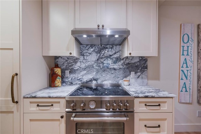 kitchen featuring high end range, under cabinet range hood, decorative backsplash, and light stone counters