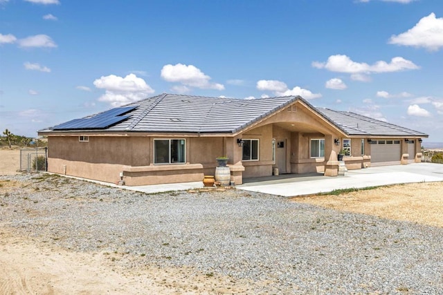 11374 Desert View Rd, Pinon Hills, CA 92372 - view of front facade featuring concrete driveway, stucco siding, roof mounted solar panels, an attached garage, and a tiled roof