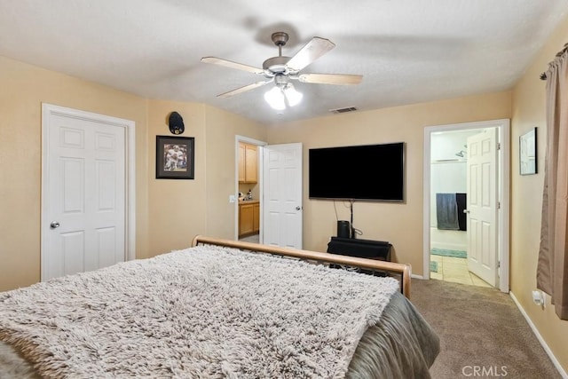 carpeted bedroom featuring baseboards, ensuite bathroom, and a ceiling fan