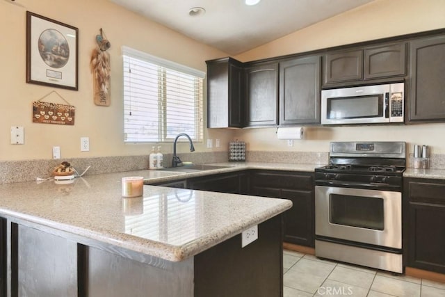 kitchen with stainless steel appliances, a sink, a peninsula, light tile patterned floors, and lofted ceiling