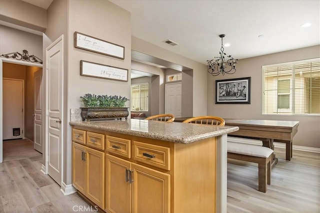 kitchen with light wood-style flooring, decorative light fixtures, baseboards, a chandelier, and light stone counters
