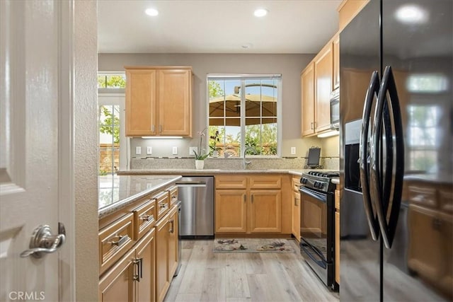 kitchen with black appliances, light wood-style floors, recessed lighting, light brown cabinets, and light stone counters