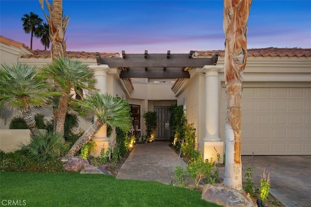 view of front of home with stucco siding, a tile roof, and an attached garage