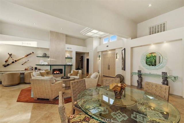 dining room featuring a towering ceiling, a tile fireplace, and recessed lighting
