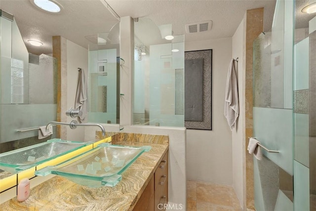 full bathroom featuring walk in shower, vanity, and a textured ceiling