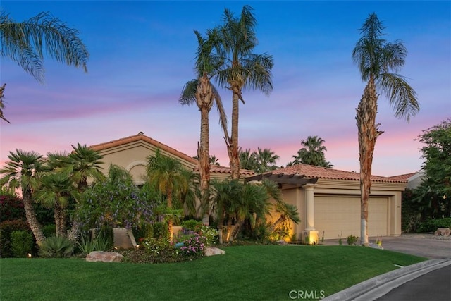 mediterranean / spanish-style house featuring a tile roof, an attached garage, stucco siding, and a front yard