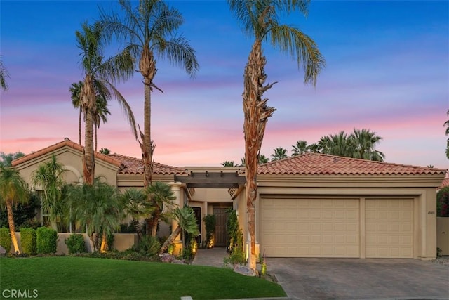 view of front of home featuring an attached garage, stucco siding, a tiled roof, driveway, and a front yard