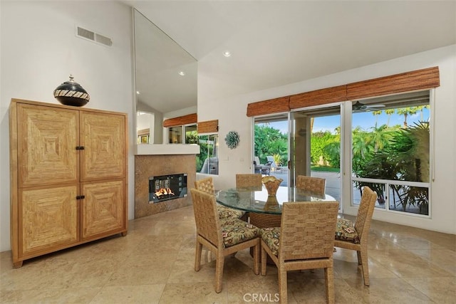 dining area featuring vaulted ceiling, a glass covered fireplace, and recessed lighting
