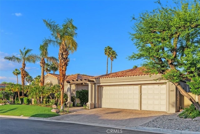 view of front of house with decorative driveway, an attached garage, stucco siding, and a tiled roof