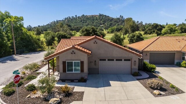 8670 Erika Ct, Atascadero, CA 93422 - mediterranean / spanish-style home with stucco siding, driveway, a garage, a tiled roof, and a view of trees