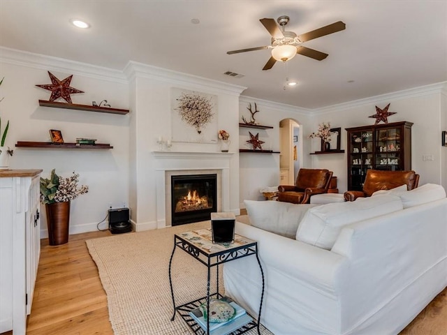 8670 Erika Ct, Atascadero, CA 93422 - living area featuring arched walkways, a ceiling fan, a glass covered fireplace, ornamental molding, and light wood-style floors