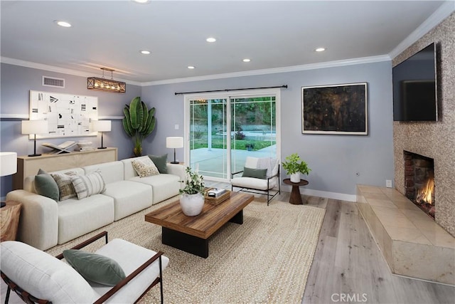 living room featuring wood finished floors, recessed lighting, ornamental molding, baseboards, and a tiled fireplace