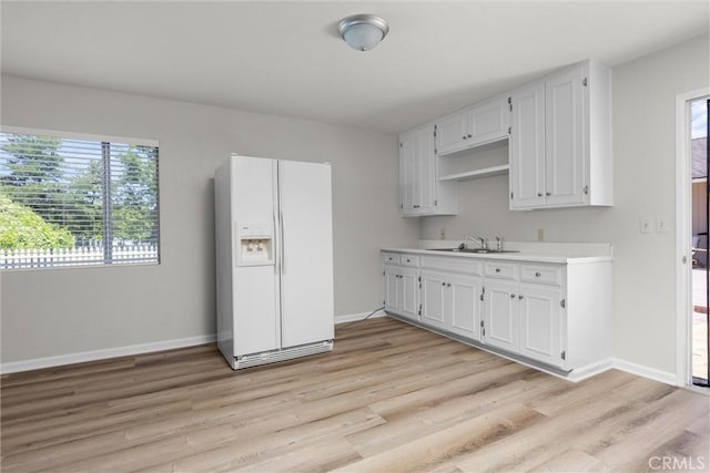 9019 San Gabriel Rd, Atascadero, CA 93422 - kitchen featuring white fridge with ice dispenser, a sink, light countertops, light wood finished floors, and white cabinets