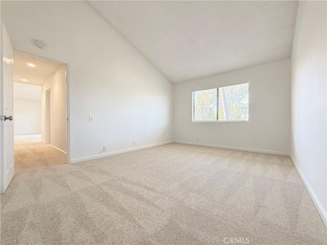 unfurnished room featuring light colored carpet, lofted ceiling, a textured ceiling, baseboards, and a smoke detector