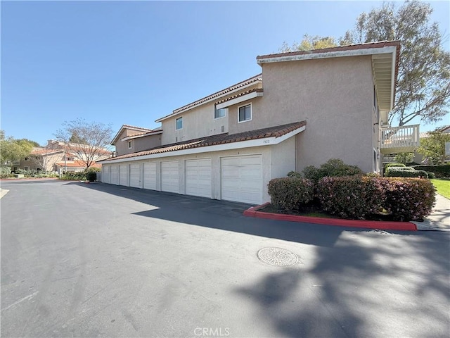 view of side of property with community garages and stucco siding