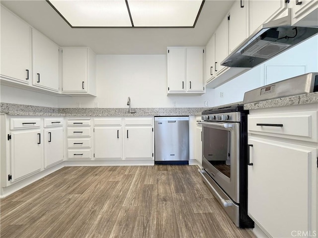 kitchen featuring appliances with stainless steel finishes, light wood-style flooring, white cabinets, a sink, and under cabinet range hood