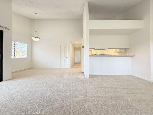 unfurnished living room featuring high vaulted ceiling, light colored carpet, baseboards, and a textured ceiling