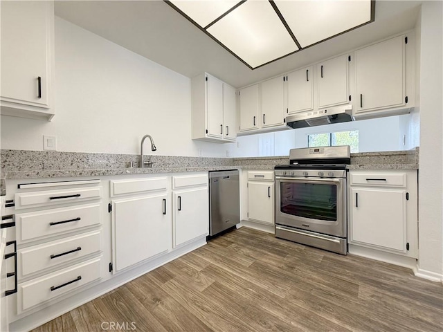 kitchen with stainless steel appliances, under cabinet range hood, light wood-type flooring, white cabinetry, and a sink