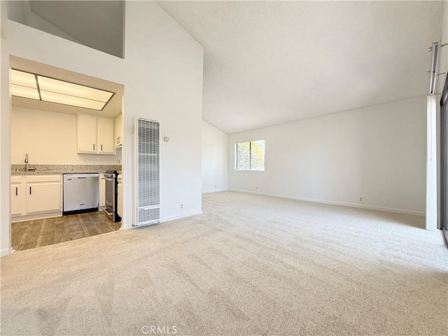 unfurnished living room with a heating unit, light colored carpet, a sink, baseboards, and high vaulted ceiling
