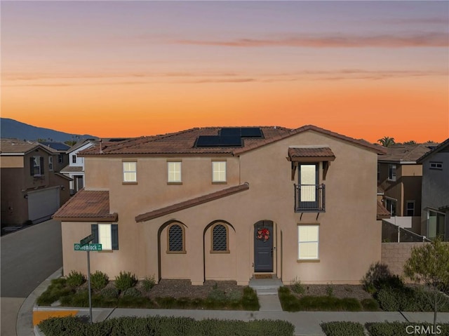 view of front of home featuring solar panels, a tile roof, stucco siding, and a mountain view