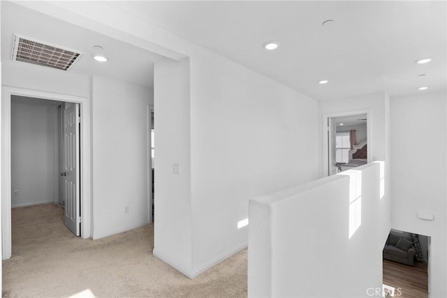 corridor featuring recessed lighting, light carpet, baseboards, and an upstairs landing