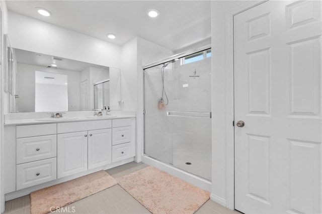 bathroom with a shower stall, double vanity, tile patterned floors, and recessed lighting
