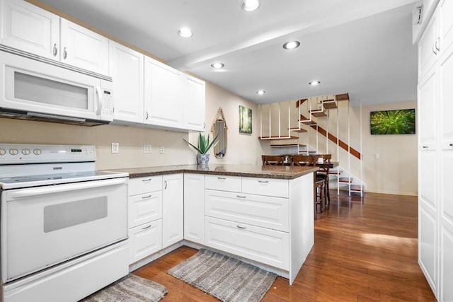 kitchen featuring a peninsula, wood finished floors, white cabinets, white appliances, and recessed lighting