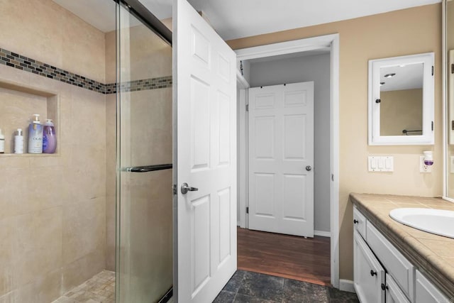 full bath with vanity, a shower stall, and wood finished floors