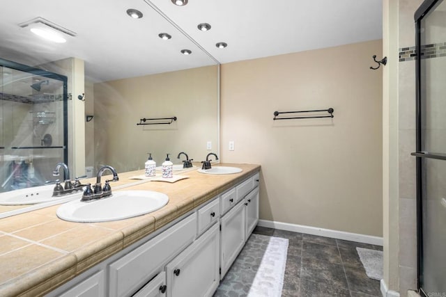 full bath featuring a sink, double vanity, baseboards, and a shower stall