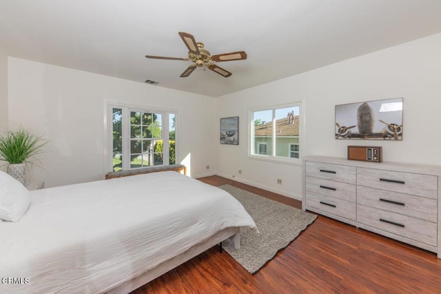 bedroom with multiple windows, wood finished floors, baseboards, and a ceiling fan