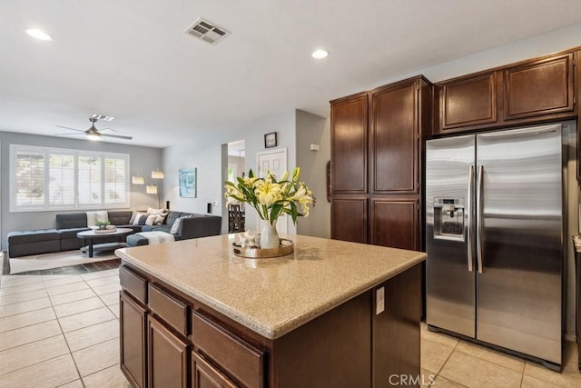 kitchen featuring stainless steel fridge, light tile patterned floors, a kitchen island, ceiling fan, and recessed lighting