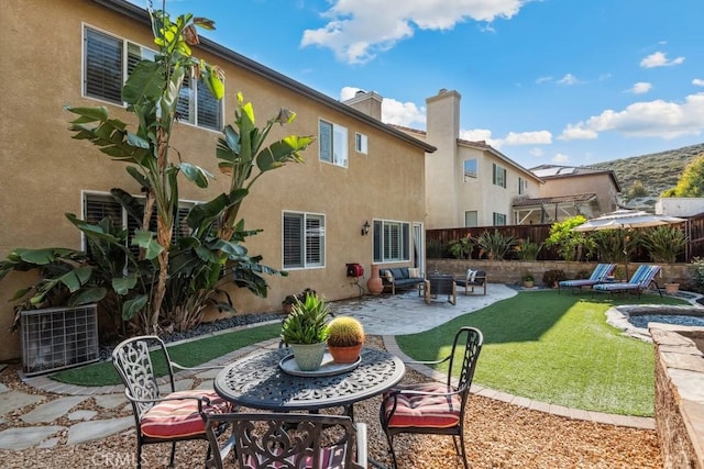 rear view of property with a patio area, stucco siding, a chimney, and central AC