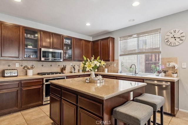 kitchen with appliances with stainless steel finishes, a sink, light tile patterned floors, backsplash, and recessed lighting