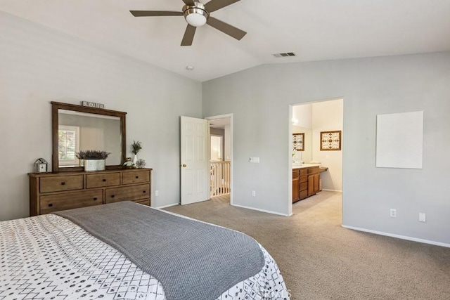 bedroom featuring lofted ceiling, light carpet, baseboards, ensuite bathroom, and a ceiling fan