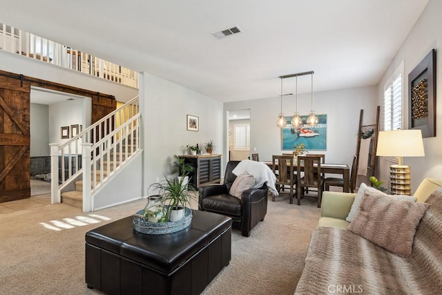 living area with carpet, a barn door, stairway, and a chandelier