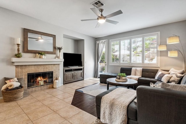 living room with a ceiling fan, light tile patterned floors, and a tiled fireplace