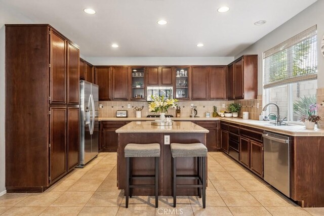 kitchen featuring stainless steel appliances, backsplash, recessed lighting, a center island, and glass insert cabinets