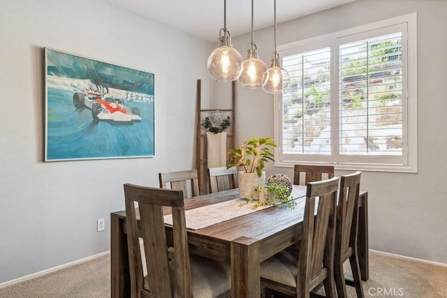 carpeted dining space with baseboards and a chandelier