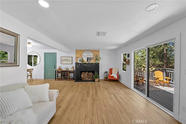 living area with light wood-style floors, a brick fireplace, and baseboards