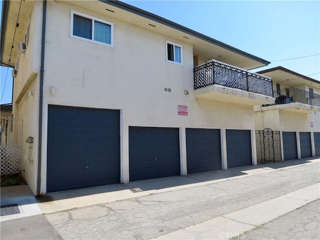 back of house with stucco siding, a balcony, and an attached garage
