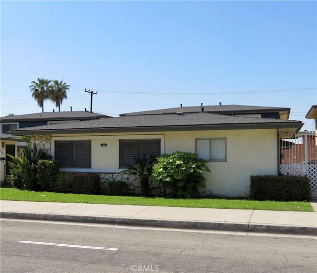 view of front of home featuring stucco siding and roof with shingles