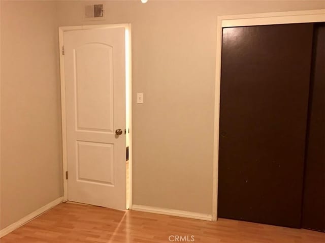 unfurnished bedroom featuring light wood-style floors, a closet, and baseboards