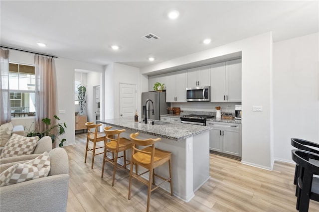 40545 Melrose Dr, Temecula, CA 92591 - kitchen featuring appliances with stainless steel finishes, open floor plan, a kitchen breakfast bar, an island with sink, and recessed lighting