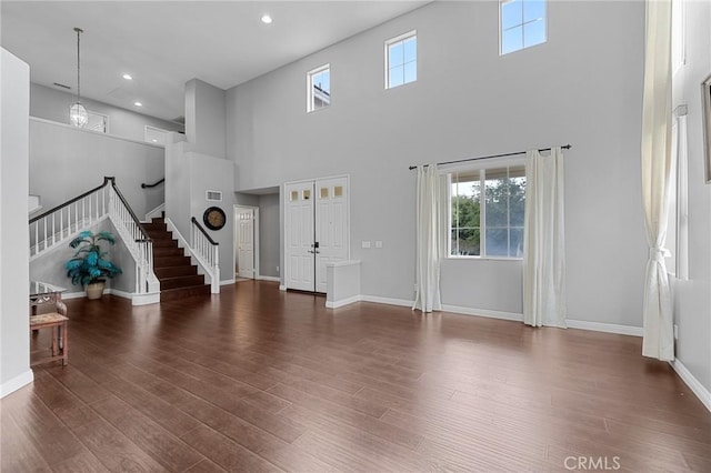 26426 Cardinal Dr, Canyon Country, CA 91387 - unfurnished living room featuring a towering ceiling, stairs, wood finished floors, recessed lighting, and baseboards