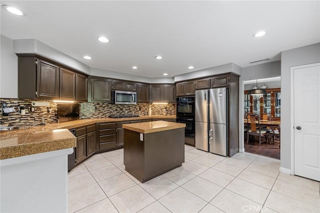26426 Cardinal Dr, Canyon Country, CA 91387 - kitchen with black appliances, tile counters, dark brown cabinets, decorative backsplash, and a center island