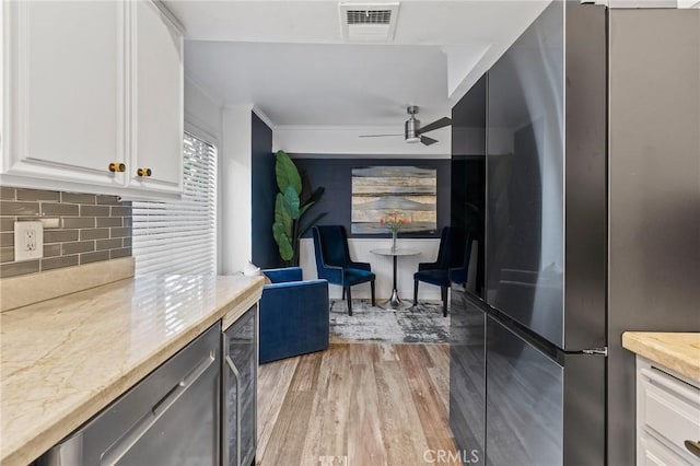 5100 Riverton Ave Unit 14, North Hollywood, CA 91601 - kitchen featuring freestanding refrigerator, light wood-style floors, backsplash, beverage cooler, and white cabinets